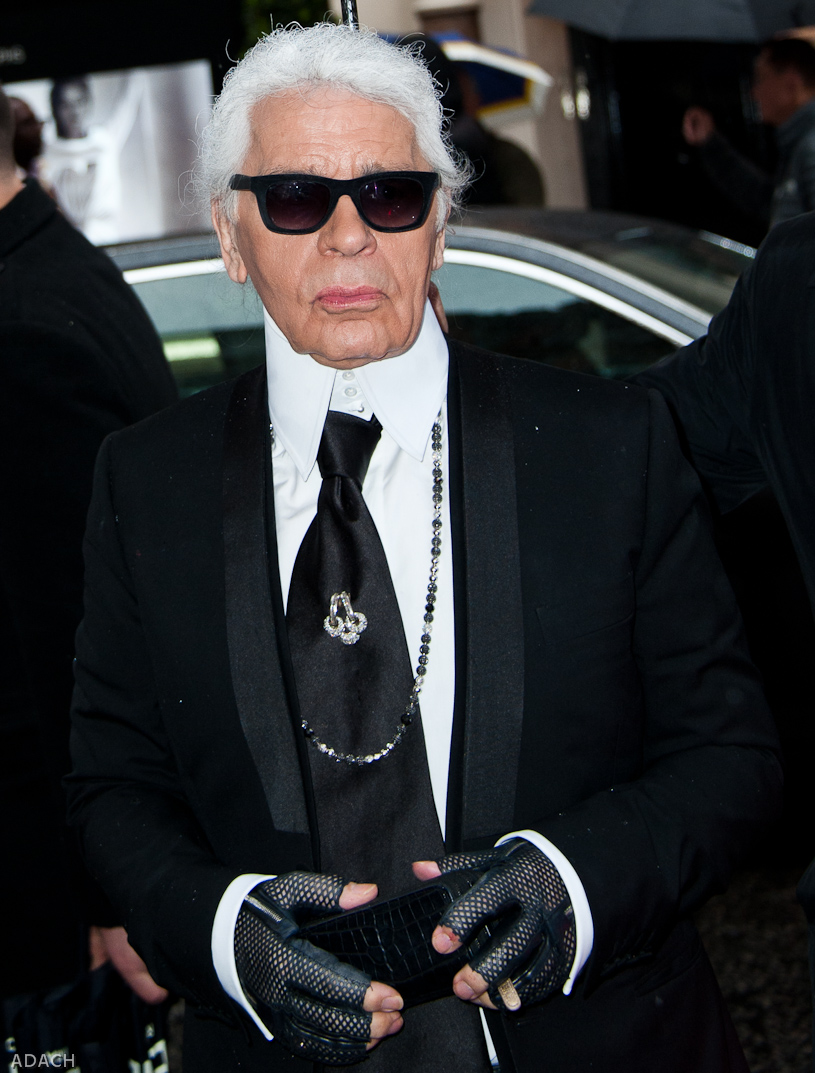 Karl Lagerfeld dressed in his famous attire of black jacket, fingerless leather gloves high white collared shirt